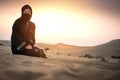 Young woman Bedouin in black traditional clothes against sunset sky over desert. Royalty Free Stock Photo