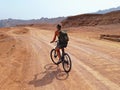 Young woman from behind riding a bike in the Sinai Peninsula. Extreme sports in the Dahab desert. desert