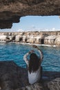 Young woman from behind is sitting in cave hole and looking at sea caves Royalty Free Stock Photo