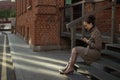 A young woman in a beige coat is sitting on the stairs Royalty Free Stock Photo