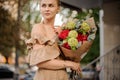 Young woman holds stylish bouquet and looks away