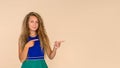 Young woman on a beige isolated background points with her fingers to a free space for an inscription