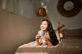 Young woman in beige pajamas lying on the bed at home.Relaxing and drinking cup of hot coffee or tea Royalty Free Stock Photo