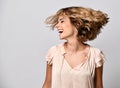 Young woman in a beige short-sleeved satin blouse shakes her head with her hair. The concept of joy, happiness, joy, fun. Royalty Free Stock Photo