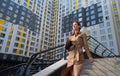 Young business woman in beige trech coat holds a laptop and walks down the stairs of a a high-rise building. Urban lifestyle Royalty Free Stock Photo