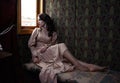 Young woman in beige vintage dress of early 20th century sitting