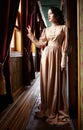 Young woman in beige vintage dress of early 20th century standin