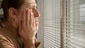 Young woman being witness of something scary or criminal while looking through window blinds Royalty Free Stock Photo