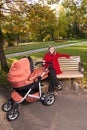 Young woman on bench with a pram.