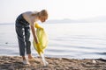 A young woman bent down and picks up an empty plastic bottle to put it in the trash bag. Royalty Free Stock Photo