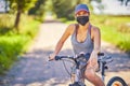 Young woman on a bike in countryside wearing a mask Royalty Free Stock Photo