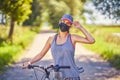 Young woman on a bike in countryside wearing a mask Royalty Free Stock Photo