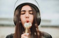 Young woman biker in bike safety helmet and leather outfit with dandelions flowers in hands Royalty Free Stock Photo