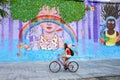 Young woman biking along colorful wall in Montevideo, Uruguay