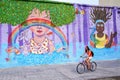 Young woman biking along colorful wall in Montevideo, Uruguay