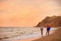 Young woman in bikini and her boyfriend on beach at sunset. Lovely couple