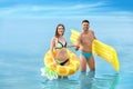 Young woman in bikini and her boyfriend with inflatable toys on beach