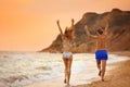 Young woman in bikini and her walking on beach at sunset. Lovely couple