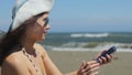 Young woman in bikini making selfie on smartphone, sharing photo on sandy beach