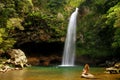Young woman in bikini sitting by Lower Tavoro Waterfalls in Bouma National Heritage Park, Taveuni Island, Fiji