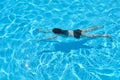 Young woman in bikini swimming underwater in an outdoor swimming pool, top view Royalty Free Stock Photo