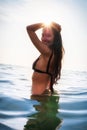 Young woman in bikini takes a bath in the sea at sunset lights in summer Royalty Free Stock Photo