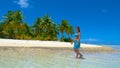 Young woman in bikini walking in the shallow ocean water and along sandy beach. Royalty Free Stock Photo