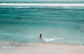 Young woman in a bikini at the white sand near the waves of blue sea. Bali, Indonesia. Aerial Shooting. Stunning tropical beach vi Royalty Free Stock Photo