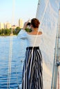 Young woman with binoculars looking into the distance and sailing on a yacht, view from the back.