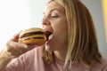 Young woman bites her mouth wide open hamburger Royalty Free Stock Photo