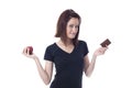 Young woman biting down on the lips torn between a chocolate bar and fresh apple