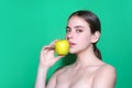 Young woman bitting apple, healthy lifestyle. Girls holds a fresh green apple studio portrait on green isolated