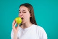 Young woman bitting apple, healthy lifestyle. Girls holds a fresh green apple studio portrait on green isolated