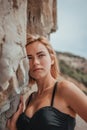 Young woman in black bikini posing on a sand rocks near the sea. Attractive young girl model posing next to volcanic Royalty Free Stock Photo