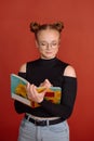 A young woman in a black blouse with a bun hairstyle writes in a notebook on a red background. university student Royalty Free Stock Photo