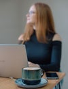 a young woman in a black blouse is doing freelance work in a cafe. female student at remote work