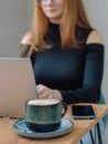 a young woman in a black blouse is doing freelance work in a cafe. female student at remote work