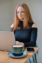 a young woman in a black blouse is doing freelance work in a cafe. female student at remote work