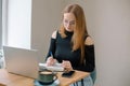 a young woman in a black blouse is doing freelance work in a cafe. female student at remote work drinks