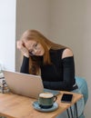 a young woman in a black blouse is doing freelance work in a cafe. female student at remote work