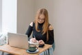 a young woman in a black blouse is doing freelance work in a cafe. female student at remote work