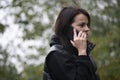 Young woman in a black coat and mask talking on the phone