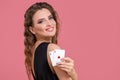 Young woman holding two aces in hand against on pink background