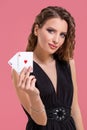 Young woman holding two aces in hand against on pink background