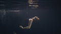 Young woman in black dress swimming underwater in pool while video shooting Royalty Free Stock Photo