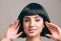 Young woman with black hair posing on camera. Attractive brunette with bob haircut. Model touching it with both hands Royalty Free Stock Photo