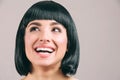 Young woman with black hair posing on camera. Brunette bob haircut. Smiling and looking up to left. Cheerful young woman Royalty Free Stock Photo