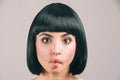 Young woman with black hair posing on camera. Freak brunette model with bob haircut. Holding lips together. Eyes look Royalty Free Stock Photo