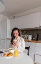 Young woman with black hair in white robe sits on chair the kitchen Royalty Free Stock Photo