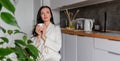 Young woman with black hair in white robe sits on chair the kitchen Royalty Free Stock Photo